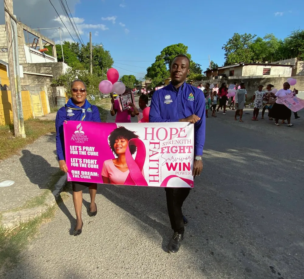 Members marching with a breast cancer awareness banner