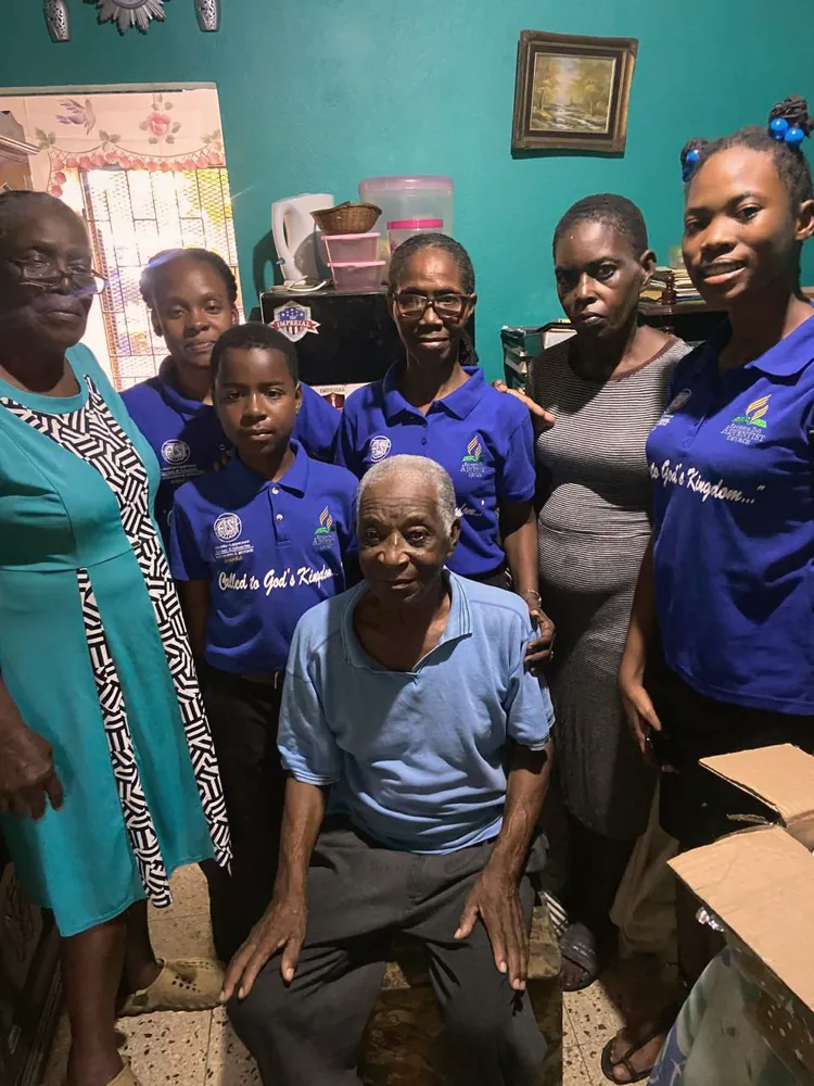 Missionaries with an elderly church member at home