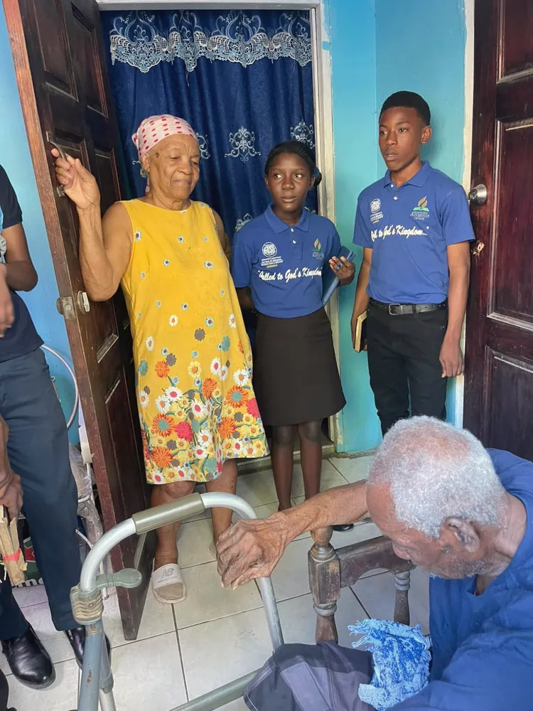 Missionaries greeting an elderly church member at the door